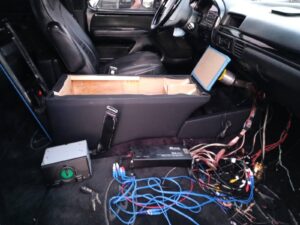 Custom car audio installation in progress with amplifier wiring and subwoofer enclosure fabrication in Orange County